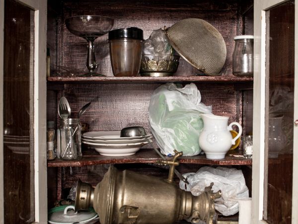 Old wooden cabinet with vintage kitchenware and utensils inside.