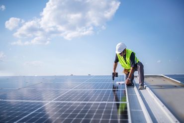 Solar technician inspecting and maintaining photovoltaic panels on a rooftop.