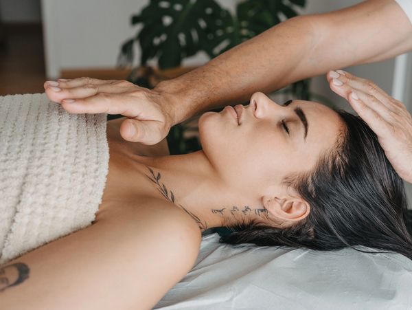 Woman receiving a relaxing healing therapy with hands over her head and chest.