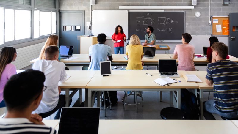 Panoramic image of multiracial students listening to african american female classmate giving oral presentation. Education concept.