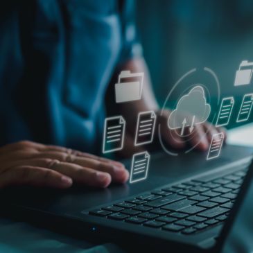 Person using laptop with digital cloud storage icons floating above keyboard.