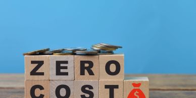 Blocks spelling zero cost with coins on top.