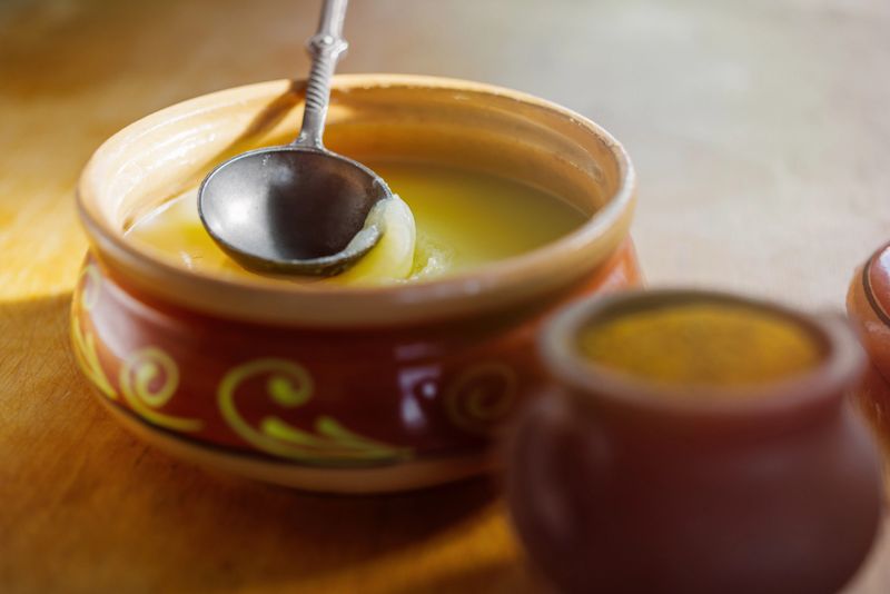 Pure OR Desi Ghee also known as clarified liquid butter. Pure OR Desi Ghee in ceramic bowls on an old wooden table.