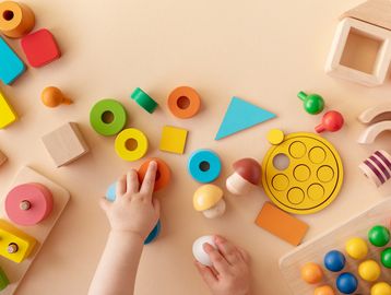 Child playing with colorful wooden educational toys on a beige surface.