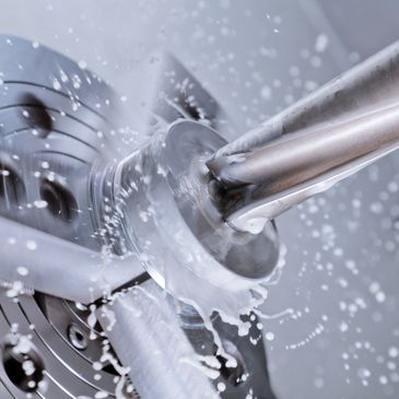 Close-up of metalworking with coolant spray during machining.