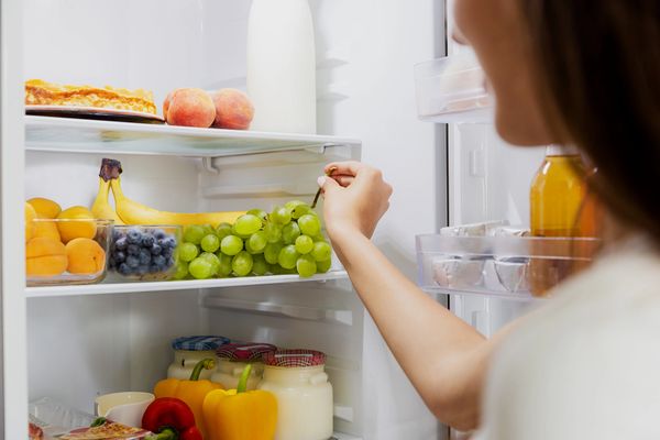 Person grabbing grapes from the fridge.