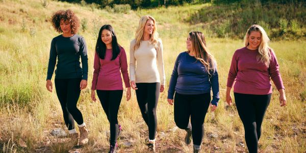 Five women walking outdoors on a sunny day.