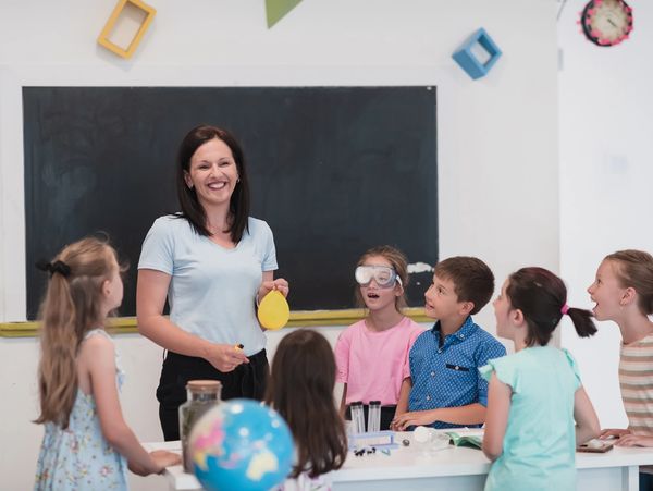 Teacher instructing a diverse group of young children sitting on the floor.