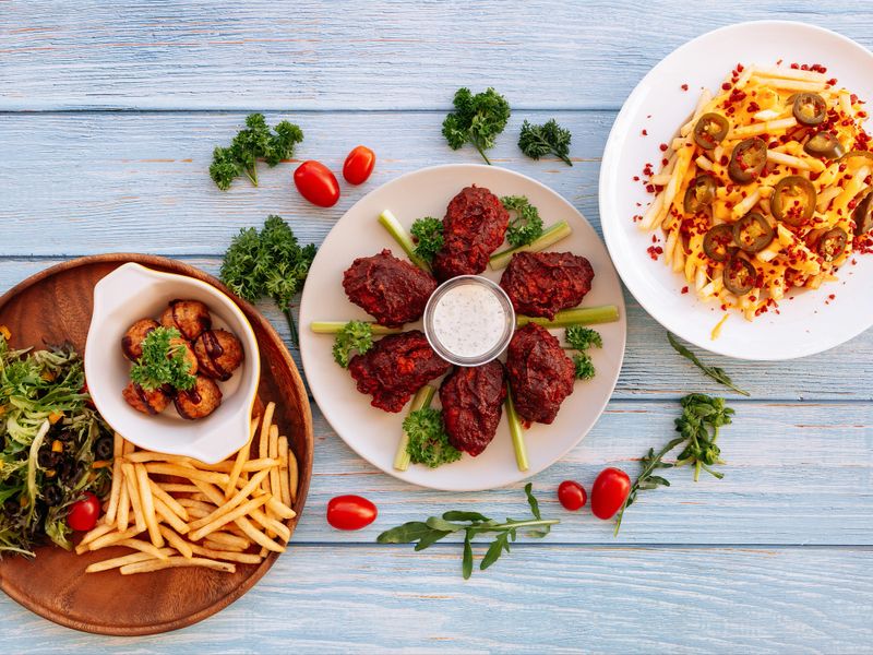Assorted fastfood Buffalo Mid Joint Wings, loaded Cheesy Fries, Meatballs with chips Served in dish isolated on wooden table top view fastfood