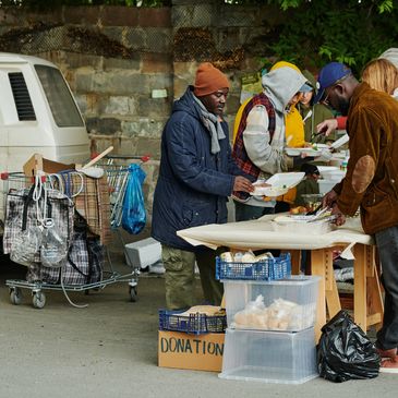People receiving food at a donation table outdoors on a cold day.