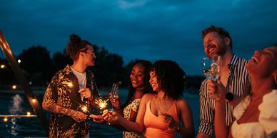 Group enjoying a nighttime celebration with drinks and sparklers.