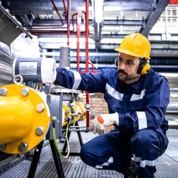 Engineer inspecting machinery in an industrial plant wearing safety gear.