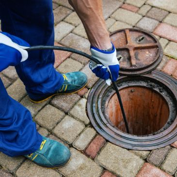 Person clearing a drain with a hose.