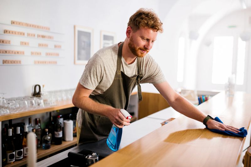 Mid adult man disinfecting bar while working in a restaurant