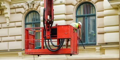 Worker cleaning building facade from lift platform.