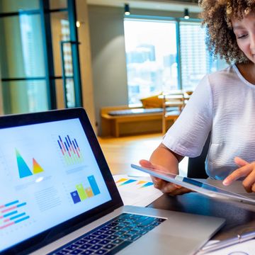 Two women discussing data charts in a modern office.