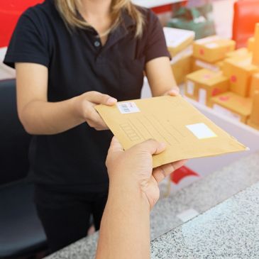 Person handing over a package envelope at a counter.
