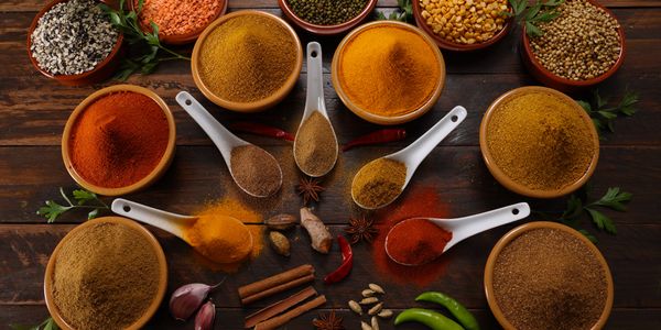Various colorful spices and lentils arranged on a wooden table.