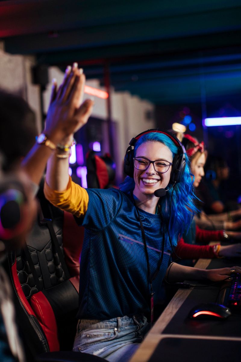 Smiling pro gamer with a headset gives a high five to her teammate