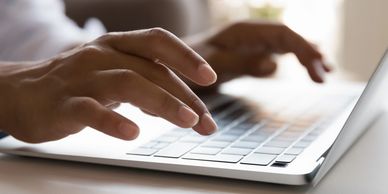 Hands typing on laptop, crafting compelling website content that connects and converts.