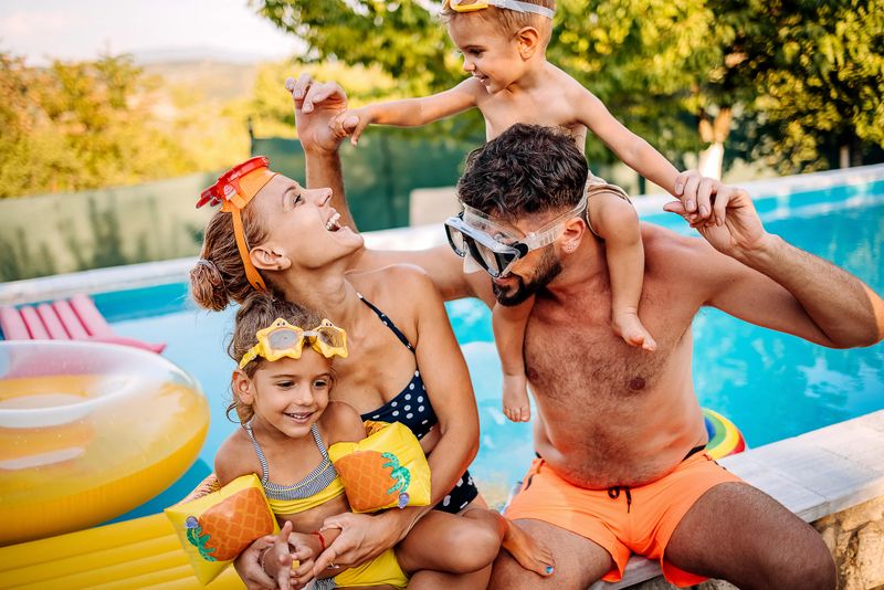 Happy family with two children at the pool, inflating swimming tires