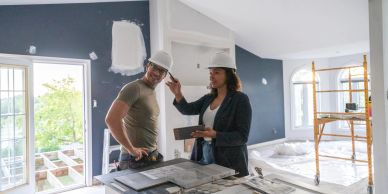 Two construction workers planning in a room under renovation.