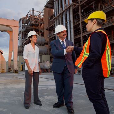 Professionals in safety gear shaking hands at an industrial site.