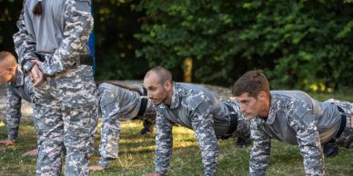 Military personnel doing push-ups outdoors.