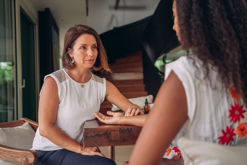 An ayurvedic therapist is checking the pulse of young woman during consultation at home.