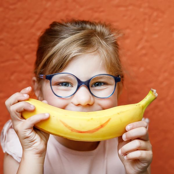 A girl holding a banana to make a smiling face