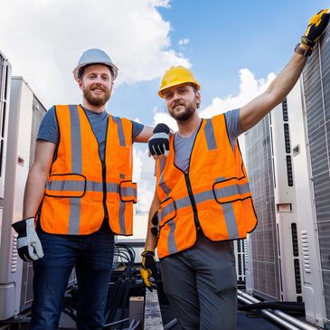 Two HVAC technicians wearing safety vests and helmets.