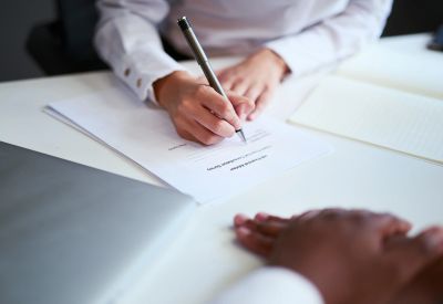 Persona firmando un documento en una oficina.
