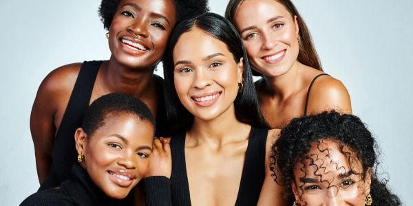 Group of five smiling diverse women posing together.