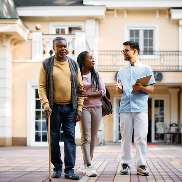 Senior living caregiver speaking with an adult daughter visiting her father.