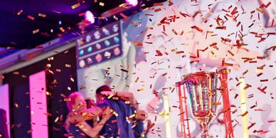 People celebrating with confetti and a trophy on stage.