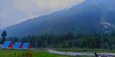 Colorful tents set in a lush green valley with misty mountains in the background.