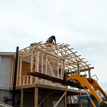 Worker building wooden frame roof on house.
