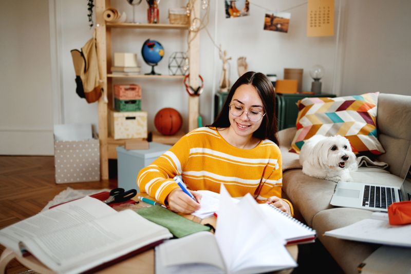 Young girl studying with her dog next to her