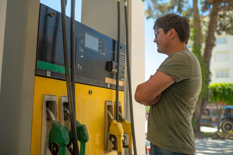 Man refueling his car and looking sad about fuel price