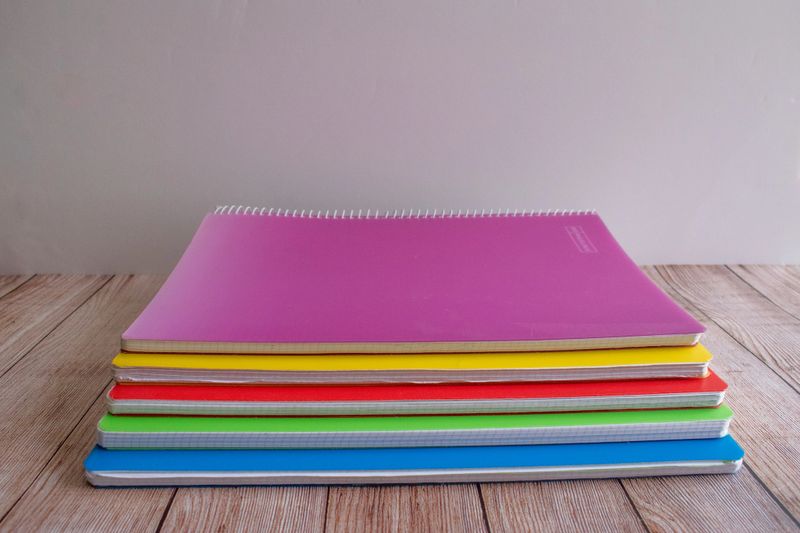 group of colored notebooks on a wooden table ready for use