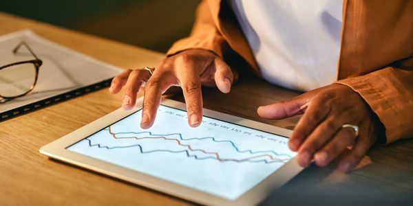 Person analyzing data on a tablet with graphs.