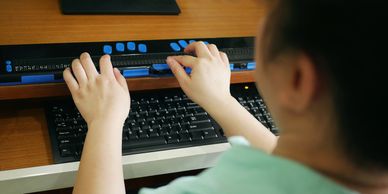 Image of student using computer keyboard and refreshable braille device in conjunction