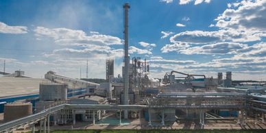Industrial refinery with chimneys and pipelines under a cloudy sky.