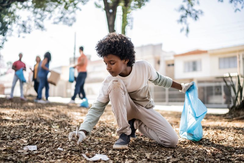 Boy picking up garbage to clean a public park