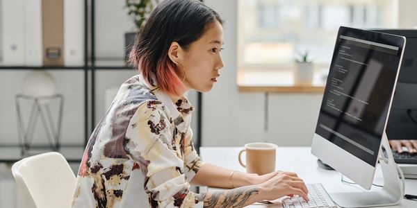 Focused woman working on a computer at a modern office desk.