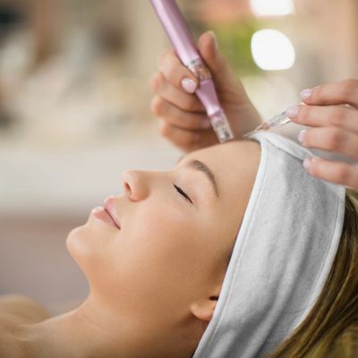 Woman receiving a facial treatment with a microdermabrasion tool at a spa.
