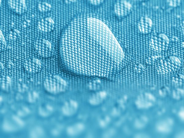 Water droplets on blue fabric close-up.