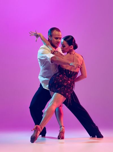 Couple performing a passionate dance under purple light.