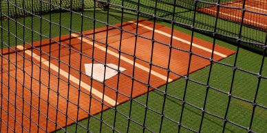View of a baseball home plate behind a protective net.