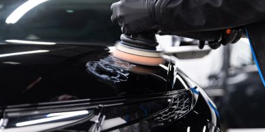 Polishing a black car with a rotary buffer.